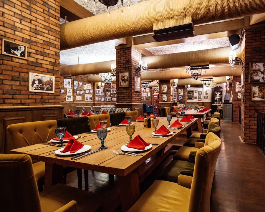 restaurant-hall-with-red-brick-walls-wooden-tables-pipes-ceiling_140725-8504